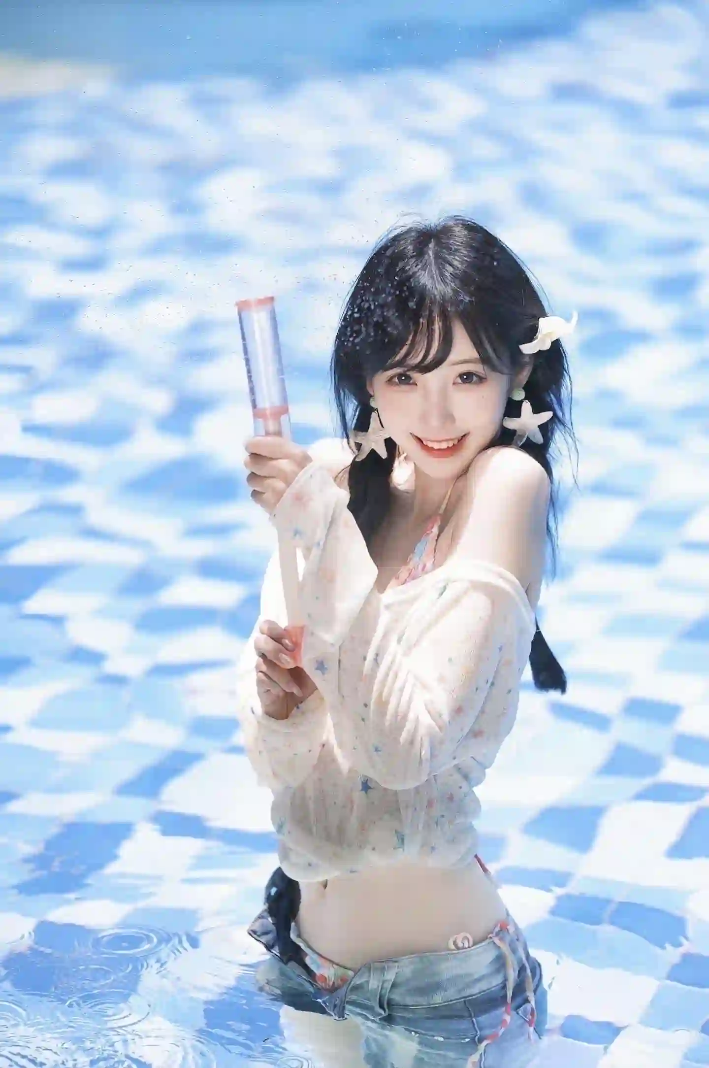 一位扎着双麻花辫的甜美少女站在泳池中，手持水枪，水花四溅，整体画面充满夏日活力与清新感。