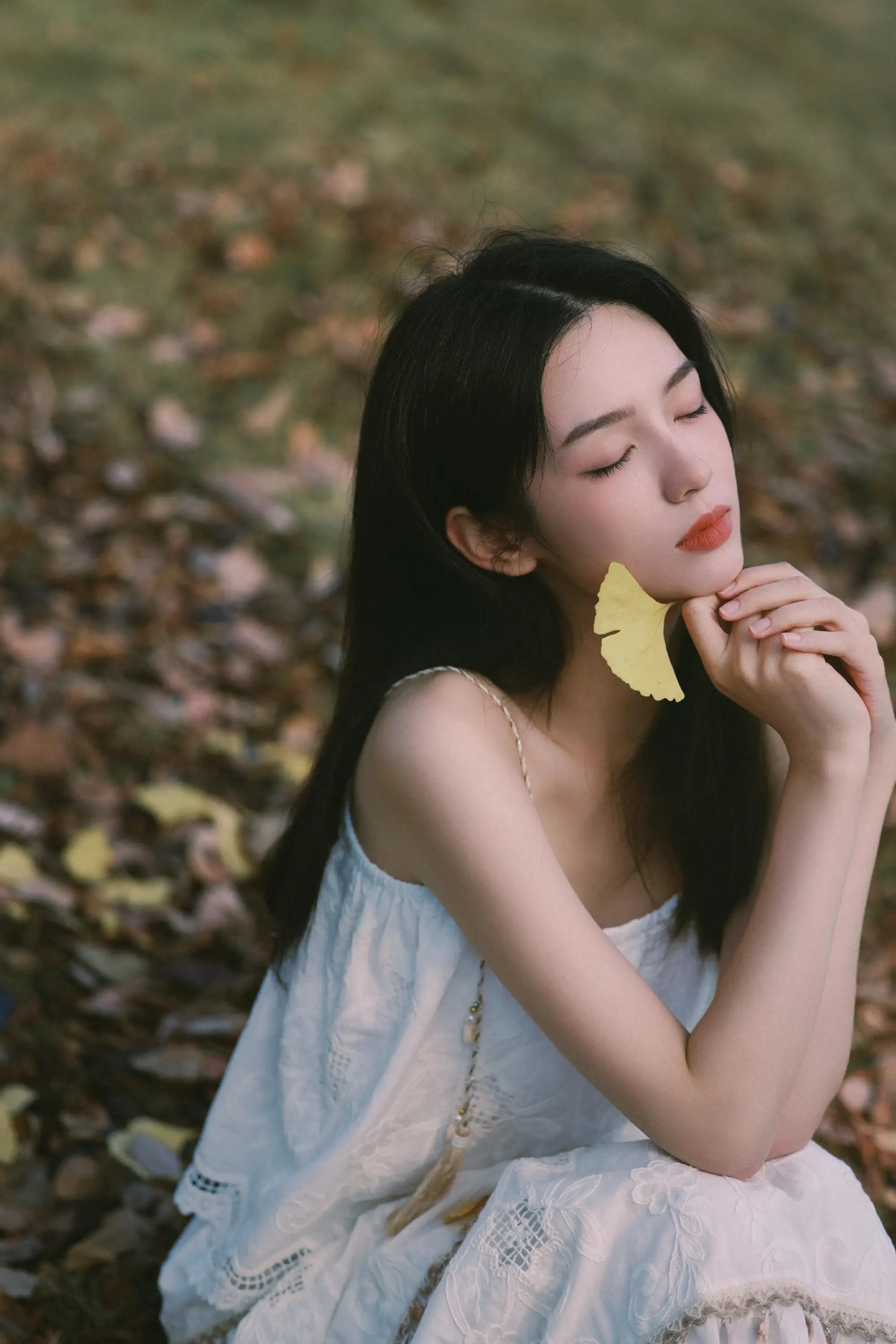 手拿一片黄色枫叶的长发白裙美女 周也