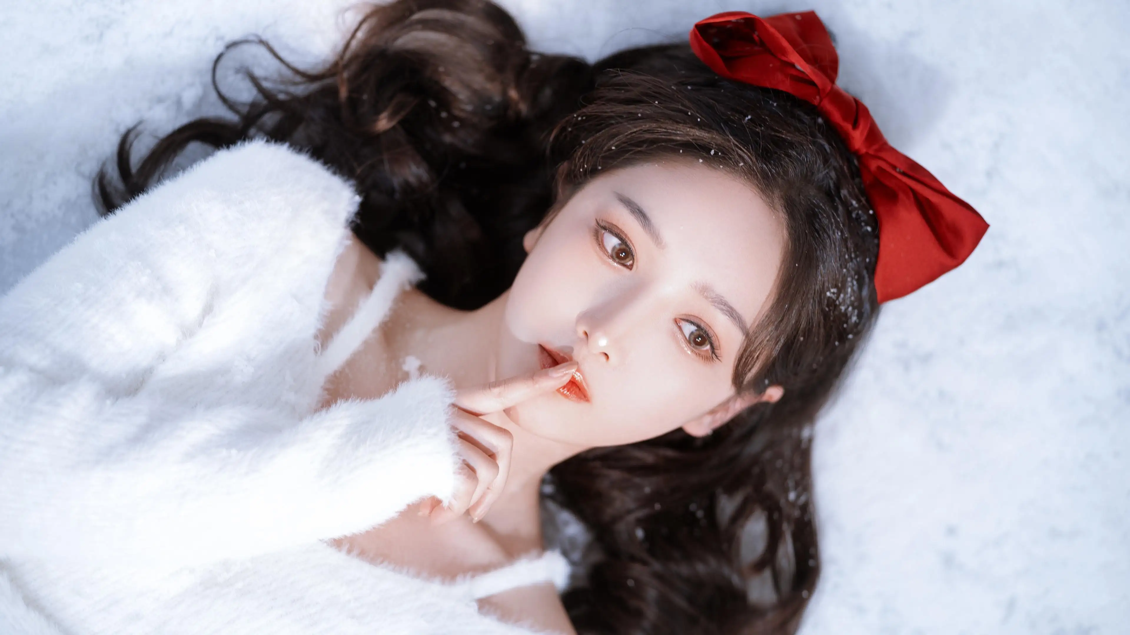 躺在雪地的美女 长头发 红色蝴蝶结 白色毛衣
