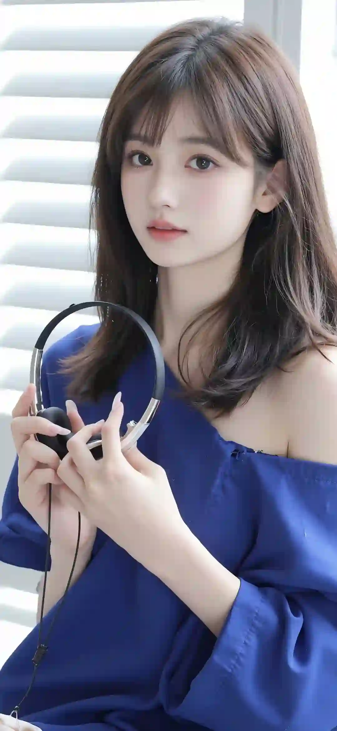 拿着耳机的长发清纯美女 蓝色衣服 漏肩穿搭