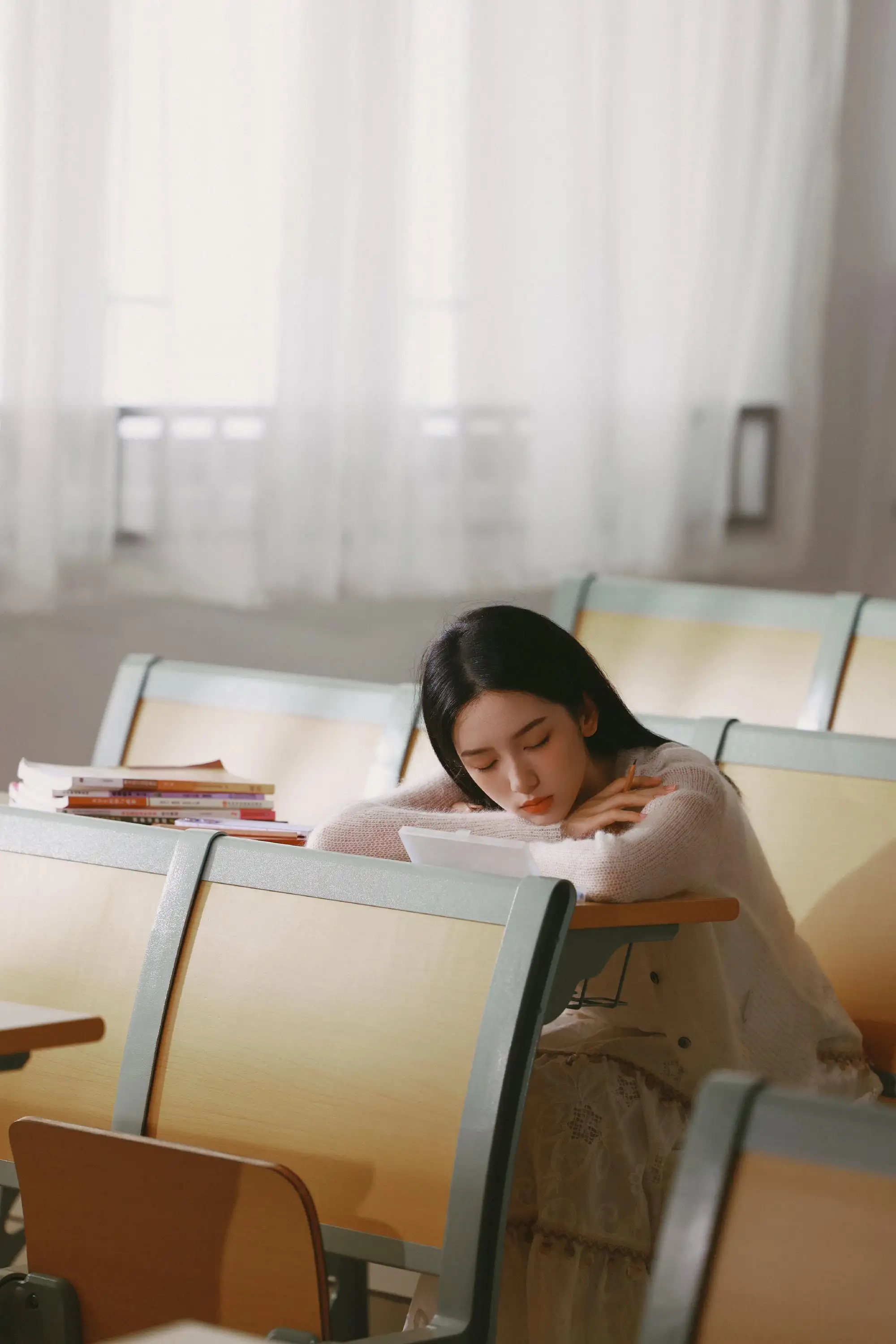 趴着课桌上休息的长发白裙美女 周也